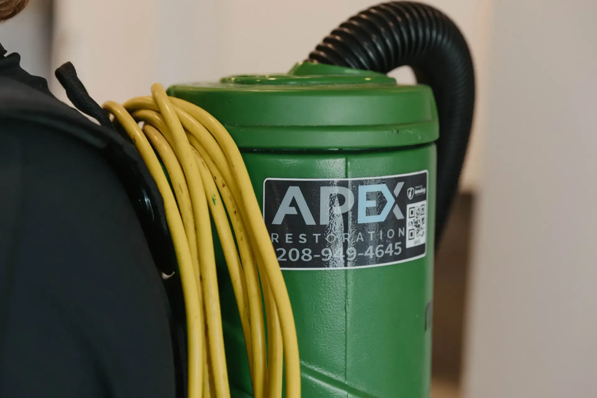 Apex Restoration decal on a green backpack vacuum, water damage restoration in Idaho and Eastern Washington