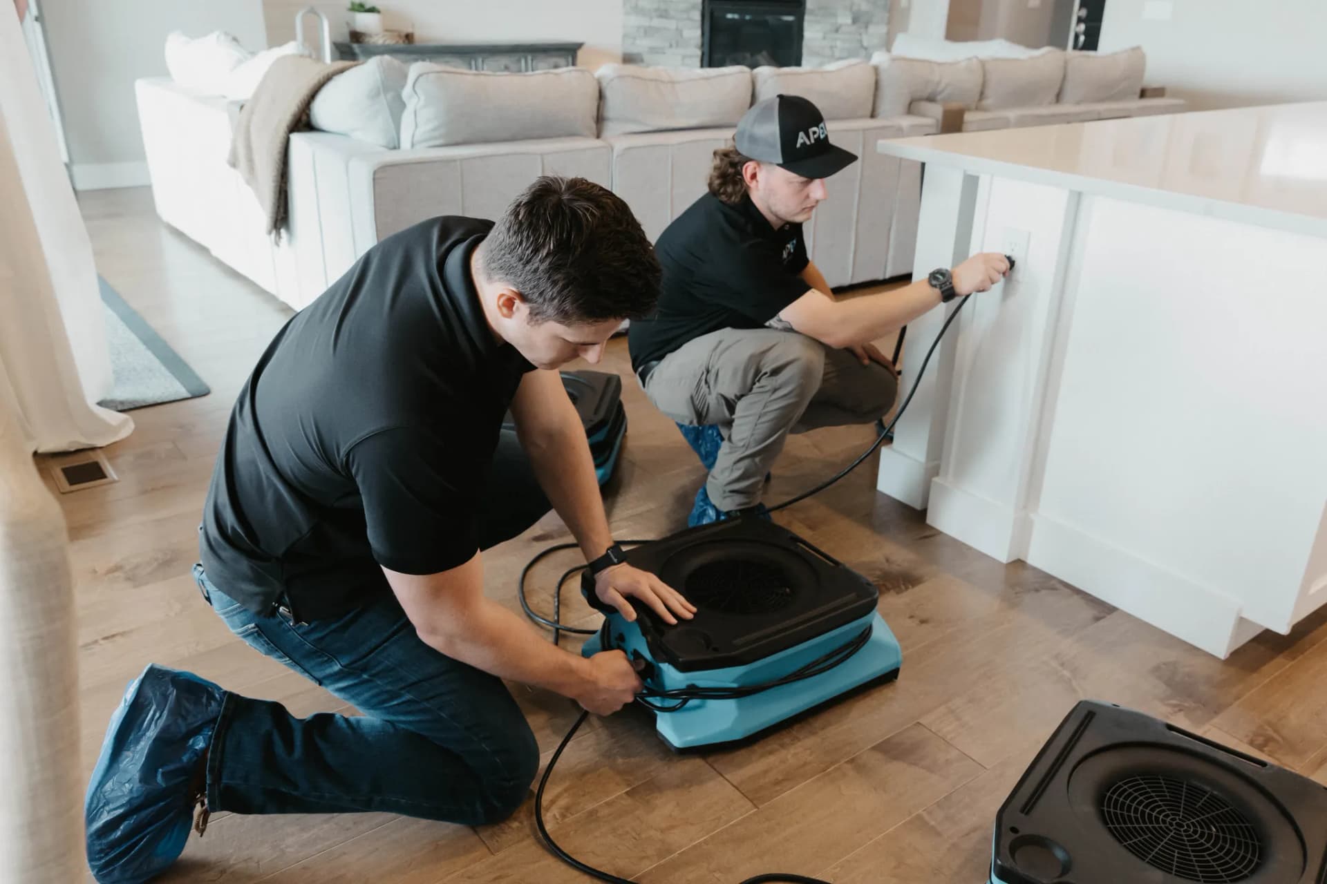 Apex Restoration technicians setting up an air mover for water damage restoration, serving Boise, ID